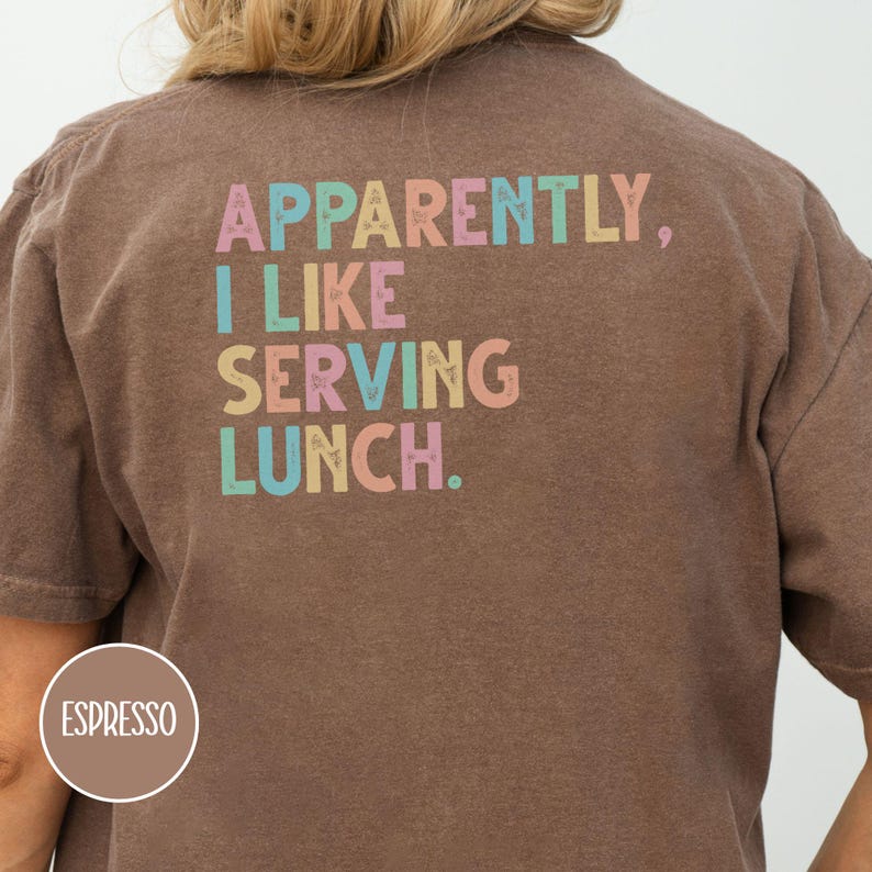 May include: Espresso-colored t-shirt with the text "Apparently, I like serving lunch" in pastel colors. The shirt is a casual style, suitable for everyday wear.