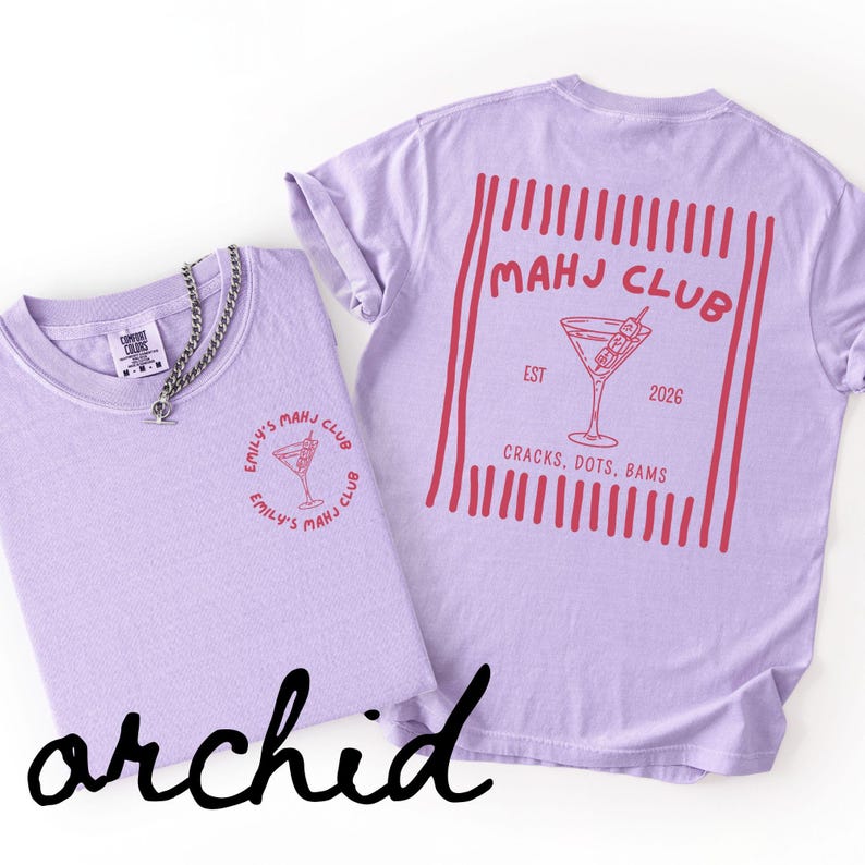 Puede incluir: Dos camisetas color orqu&iacute;dea con gr&aacute;ficos rojos. Una camiseta presenta un peque&ntilde;o dise&ntilde;o circular con una copa de c&oacute;ctel y texto. La otra camiseta tiene un dise&ntilde;o m&aacute;s grande en la espalda con una copa de c&oacute;ctel y el texto "MAHJ CLUB".