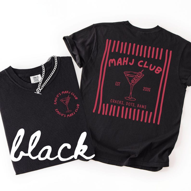 Puede incluir: Dos camisetas negras con gr&aacute;ficos rojos. Una camiseta presenta "Emily's Mahj Club" y una copa de c&oacute;ctel. La otra muestra "Mahj Club" con una copa de c&oacute;ctel, el a&ntilde;o 2026 y el texto "Cracks, Dots, Bams". Tambi&eacute;n se ve un collar de cadena plateada.