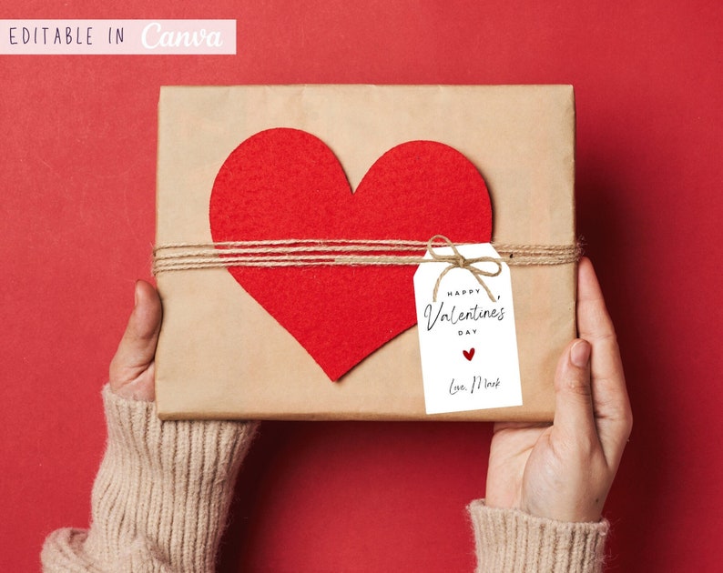 May include: A brown gift box tied with twine and a red felt heart. A white gift tag with the text "Happy Valentine's Day" and a small red heart is attached to the twine. The text "Love, [Name]" is written below the heart.