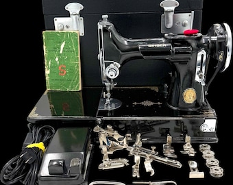 May include: A black Singer sewing machine with a matching black carrying case, a green instruction manual, a black foot pedal with a power cord, and various metal sewing attachments, presser feet, and bobbins arranged on a flat surface.