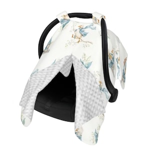 Könnte beinhalten: Weißer Baby-Autositzbezug mit einem skurrilen Muster einer Ente mit blauem Schal und Mantel. Der Bezug hat ein weiches, graues, strukturiertes Futter und einen schwarzen Griff.