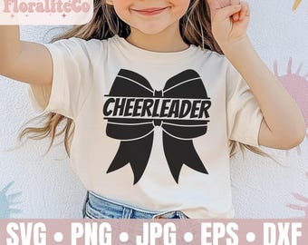 Może przedstawiać: Biała koszulka z czarną kokardką i nadrukiem "CHEERLEADER". Koszulkę nosi młoda osoba.