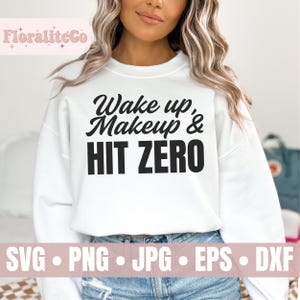 May include: White sweatshirt with black text that reads "Wake up, Makeup & Hit Zero".