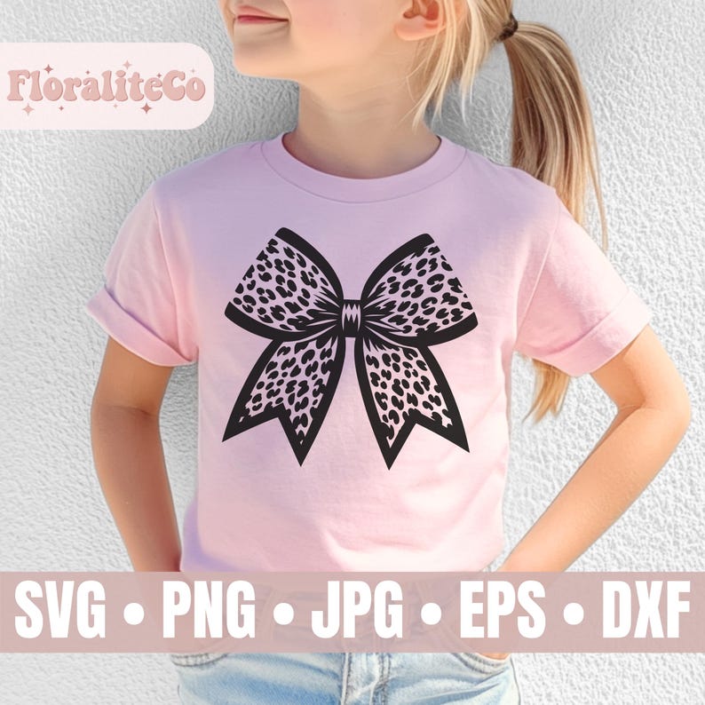 Op de afbeelding: Een roze T-shirt met een zwart-wit luipaardprint strikdesign. Het ontwerp is gecentreerd op het shirt. Het shirt wordt gedragen door een kind.
