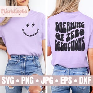 May include: A purple t-shirt with a black graphic of a smiley face with lightning bolts and the text "Dreaming of Zero Deductions".