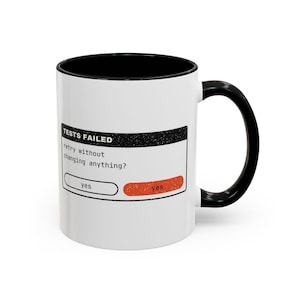 May include: A white ceramic mug with a black interior and handle. The front features a black rectangular graphic resembling a computer error message with the text: TESTS FAILED, retry without changing anything?, and two yes buttons.