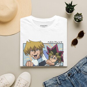 Pode incluir: Uma t-shirt branca de gola redonda com uma impressão gráfica de duas personagens de anime, uma com cabelo loiro espetado e outra com cabelo multicolorido, com o texto japonês "ベストフレンド" acima da moldura retangular e "LisaxcivArt on Etsy" dentro da gola.
