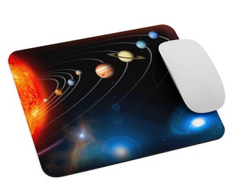 May include: A rectangular mouse pad featuring a vibrant space-themed graphic of the solar system with the sun on the left, orbiting planets, and a distant galaxy on the right. A smooth, white wireless computer mouse rests on the right side.