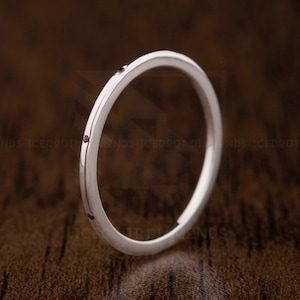 May include: A thin silver band ring with four small red gemstones set into the band.