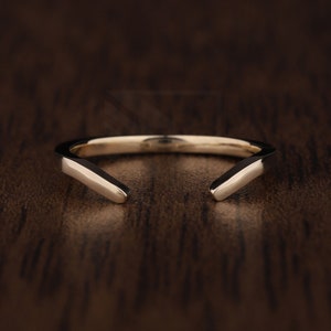 May include: A simple, minimalist gold ring with a unique, angular design. The ring is open on one side, creating a V-shape.