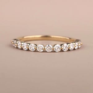 May include: A delicate gold band ring with a row of small, round diamonds set in a pave setting.