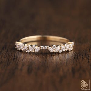 Op de afbeelding: Een delicate gouden ring met een gebogen ontwerp met een rij marquise-vormige diamanten.