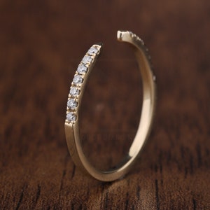 Puede incluir: Un anillo de banda de oro con una fila de pequeños diamantes engastados en la banda.