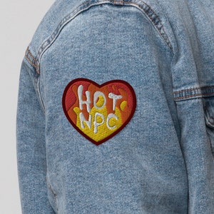 May include: A light blue denim jacket with a sherpa collar and a red, yellow, and white heart-shaped patch that says "HOT NPC".