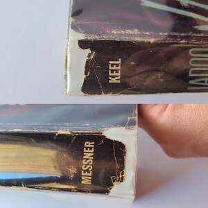 May include: Close-up of the side of two books with the titles "Keel" and "Messner" visible. The book edges are worn and show signs of age, with a distressed, vintage aesthetic. The books have a dark color scheme.
