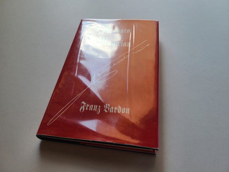 Puede incluir: Un libro de tapa dura rojo con un t&iacute;tulo y un nombre de autor blancos. El t&iacute;tulo es "Initiato en Magia" y el autor es "Franz Bardon".