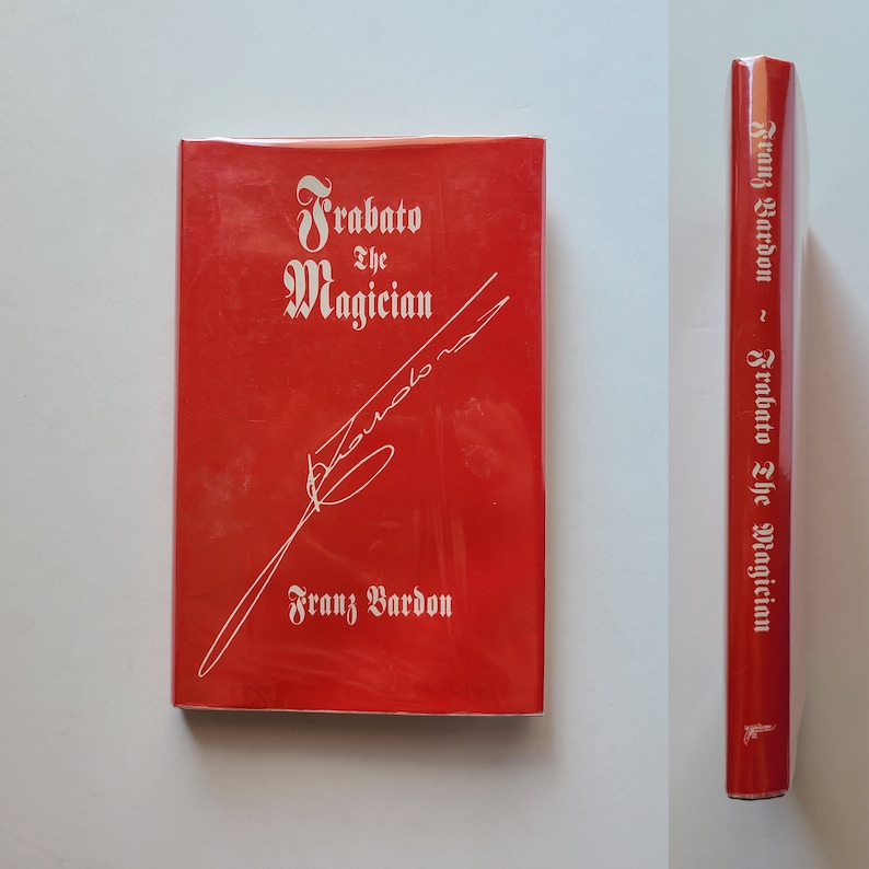 Puede incluir: Un libro de tapa dura rojo titulado "Frabaato el Mago" de Franz Bardon. El libro tiene una firma blanca en la portada.