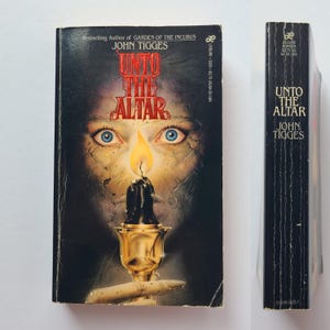 May include: A mass market paperback book titled Unto the Altar by John Tigges. The cover features a dark, cracked face with bright blue eyes, a lit candle in a gold chalice, and red text. The black spine displays the title, author, and publisher.