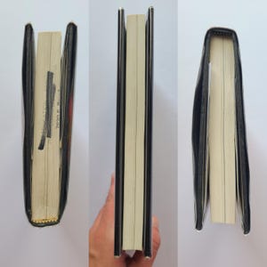 Pu&ograve; includere: Un libro con copertina rigida con una copertina nera e pagine color crema. Il dorso &egrave; visibile e il libro &egrave; aperto, rivelando il testo sulle pagine. Il libro sembra essere in buone condizioni.