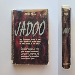 May include: A vintage copy of "Jadoo" by John Keel. The book's cover has the title in large, light green letters on a dark red and black background. The spine also shows the title and author. The book explores black magic.
