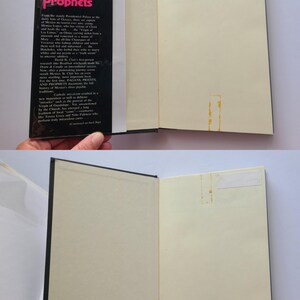 Pu&ograve; includere: Un libro aperto intitolato "Pagans, Priests, and Prophets" con copertina nera e pagine bianche. Il dorso del libro mostra il titolo in testo rosa e bianco. Il libro &egrave; tenuto aperto, rivelando le pagine interne.