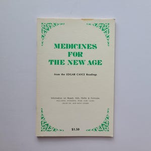 May include: A vintage book titled "Medicines for the New Age" from the Edgar Cayce Readings. The cover is off-white with green text and decorative corner designs. The book lists information on beauty aids, herbs, and formulas.