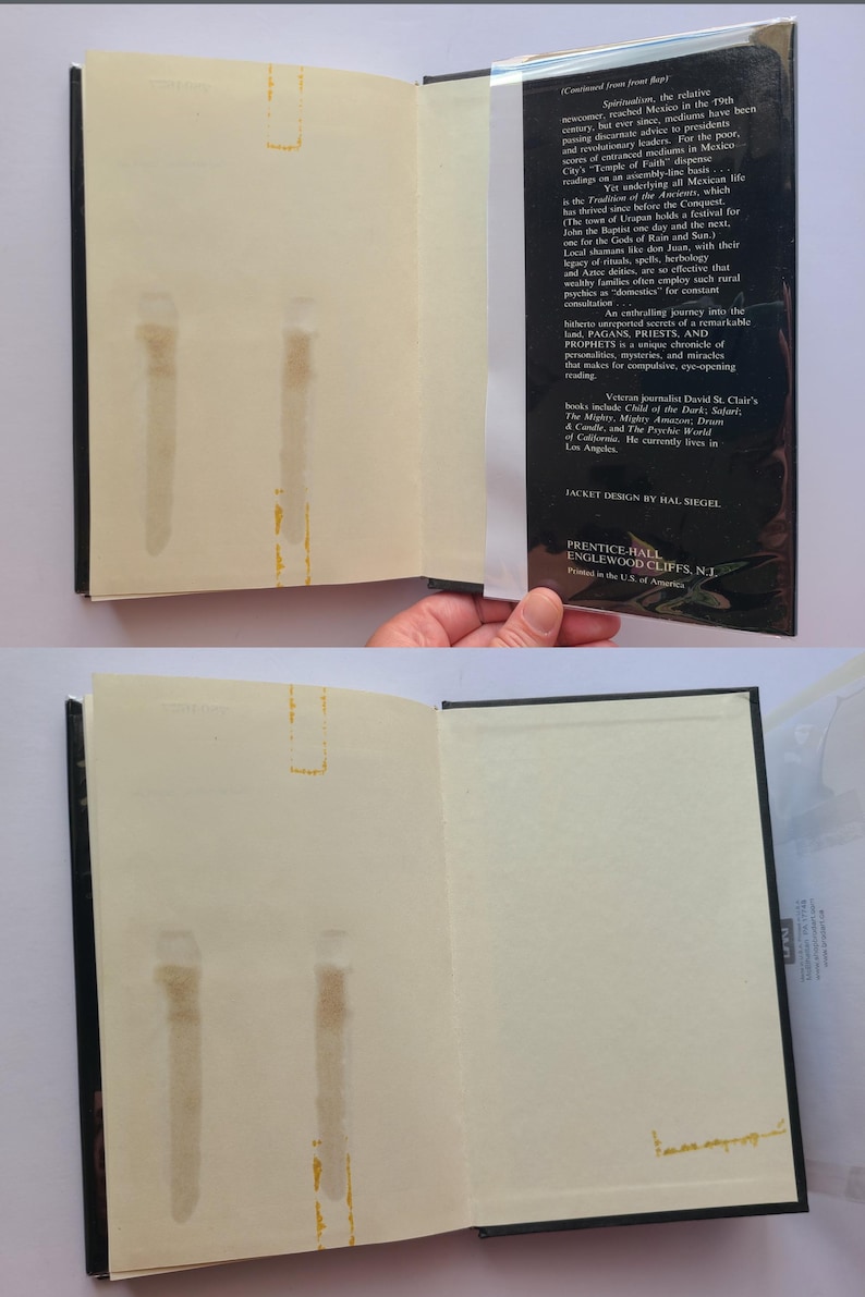 Pu&ograve; includere: Un libro aperto con copertina nera e pagine bianco sporco. La pagina di destra ha del testo, mentre quella di sinistra presenta delle macchie. La sovraccoperta del libro &egrave; visibile, con testo sul contenuto e il design del libro.