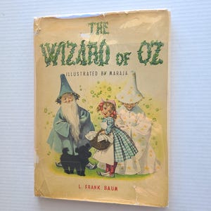 May include: Vintage copy of "The Wizard of Oz" book, illustrated by Maraja. The cover features illustrations of characters from the story, including the Wizard, Dorothy, and a black dog. The title is in green, leafy lettering.