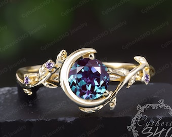 Pode incluir: Um anel de ouro com um design de lua crescente e uma grande gema redonda roxa e verde. O anel é adornado com gemas roxas menores na banda.