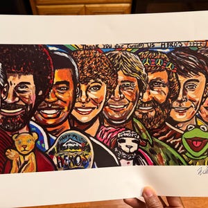 May include: A colorful painting featuring portraits of several smiling people, including Bob Ross and Kermit the Frog. The artwork includes the text "Thank You for Giving Us Hero's". A teddy bear and a sheep are also depicted.