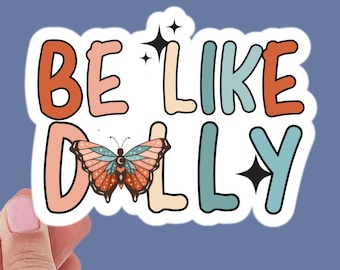 May include: A sticker with the text "Be Like Dolly" in colorful letters. A butterfly with orange and brown wings is in the center of the sticker.