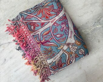 May include: A blue and red patterned throw blanket with fringed edges. The blanket features a floral design with a tree motif.