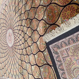 May include: An ornate, beige and brown area rug with a central circular design and a repeating pattern of curved lines and floral motifs. The rug has a dark border and fringed edges, showcasing a traditional aesthetic.