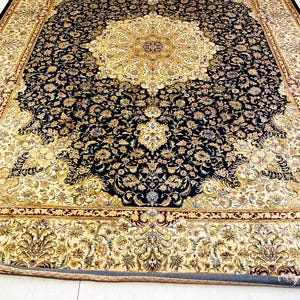 May include: A large, rectangular area rug with an intricate floral design. The rug features a central medallion in shades of gold and cream, surrounded by a deep navy blue field filled with floral patterns. The border is cream with floral motifs.