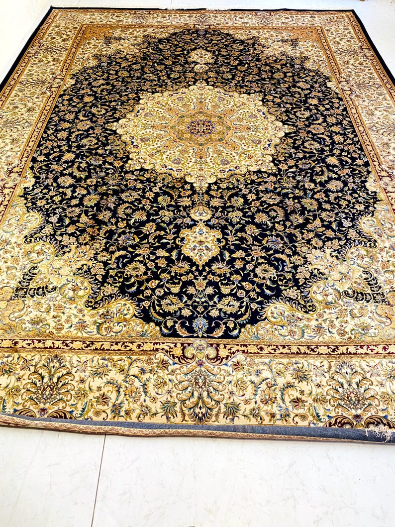 May include: A large, rectangular area rug with an intricate floral design. The rug features a central medallion in shades of gold and cream, surrounded by a deep navy blue field filled with floral patterns. The border is cream with floral motifs.