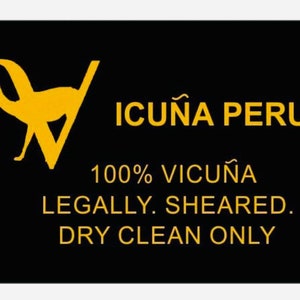 May include: A black and yellow label with a silhouette of two llamas and the text "ICUNA PERU 100% VICUNA LEGALLY SHEARED. DRY CLEAN ONLY."