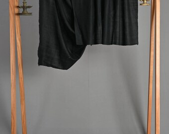 Könnte beinhalten: Zwei schwarze Stoffscharfs hängen an einem hölzernen Kleiderständer mit Rollen. Der Ständer hat eine Holzablage und zwei dekorative Hängeketten mit Metallornamenten.