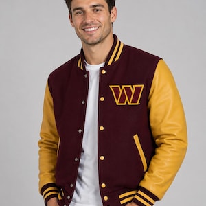 Może przedstawiać: Bordowa i złota kurtka typu varsity z dużym logo "W" na piersi. Kurtka posiada złote skórzane rękawy, pasiasty kołnierz, mankiety i dół. Kurtka ma zapięcie na guziki i klasyczny sportowy styl.