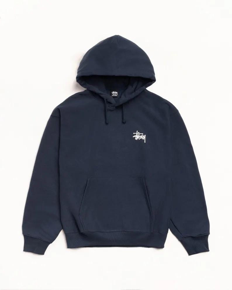 May include: Navy blue hooded sweatshirt with a front kangaroo pocket and white logo on the chest. The sweatshirt has a drawstring hood and ribbed cuffs and hem. A casual, comfortable garment.