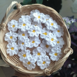 May include: A wicker basket filled with crocheted white daisy flowers with yellow centers.