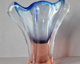 May include: A clear glass vase with a blue and pink ombre effect. The vase has a wide, flared opening and a narrow base.