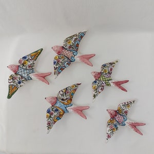 May include: Five ceramic swallow figurines with colourful, intricate designs. Each swallow has a different pattern and colour scheme, featuring shades of blue, green, pink, and white.
