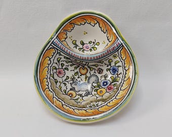 May include: A hand-painted ceramic dish with a squirrel and floral design. The dish has a white base with orange, yellow, blue, and pink accents. The rim is scalloped and the dish has a small upper compartment.