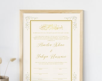May include: A gold and white wedding certificate with an Islamic calligraphy design. The certificate is framed in a light wood frame. The text on the certificate reads "In the name of Allah, the Most Gracious, the Most Merciful." The certificate is for Amelia Khan and Yahya Hussain.