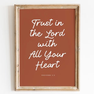Puede incluir: Una impresión enmarcada con un fondo de color óxido y texto blanco que dice "Confía en el Señor con todo tu corazón" y "Proverbios 3:5".