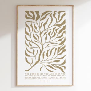 Op de afbeelding: Een ingelijste kunstdruk met een goudkleurig boomontwerp op een witte achtergrond. Het kunstwerk bevat de tekst "THE LORD BLESS YOU AND KEEP YOU" en andere gerelateerde tekst. De print is ingelijst in een houten frame.