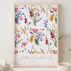 Può includere: Una stampa floreale incorniciata con illustrazioni ad acquerello di fiori selvatici colorati nei toni del rosa, arancione, giallo e blu su sfondo bianco. La stampa include il testo "Rooted and grounded in love" e "Efesini 3:17".