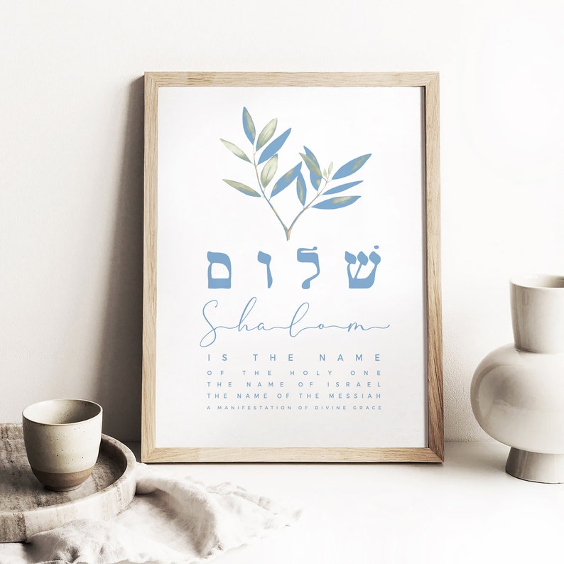 May include: A framed print featuring a blue and green olive branch design. The Hebrew word "Shalom" is written in blue letters, with the English translation "Shalom" written in cursive script below. The text "Is the name of the Holy One, the name of Israel, the name of the Messiah, a manifestation of divine grace" is written in black below the cursive word "Shalom".