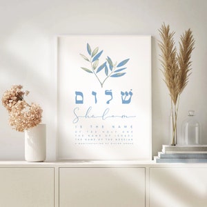 May include: A printable wall art design featuring a blue watercolour olive branch with the Hebrew word "Shalom" written in blue letters. The text below reads "Shalom is the name of the Holy One, the name of Israel, the name of the Messiah, a manifestation of divine grace."